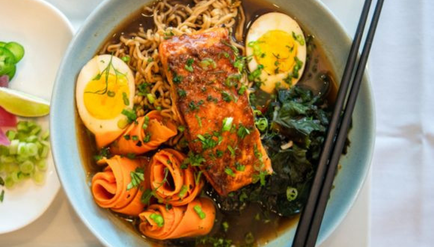 Ramen at Stardust Cafe in Lewisburg, WV with salmon, soft-boiled egg, and vegetables, accompanied by a side of fresh greens.