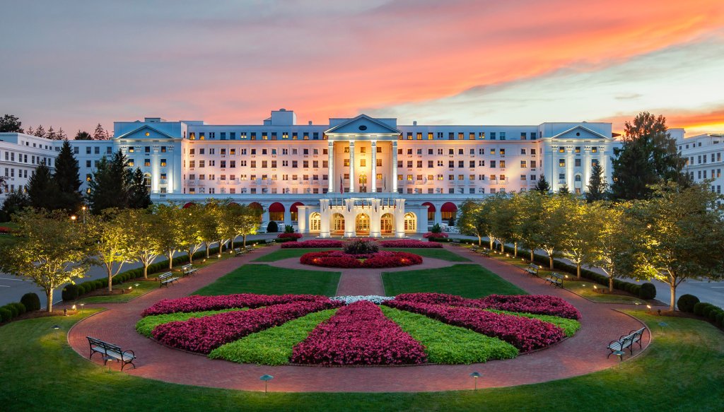 The Greenbrier Resort's grand hotel illuminated by a stunning sunset, casting warm hues across the sky and building.