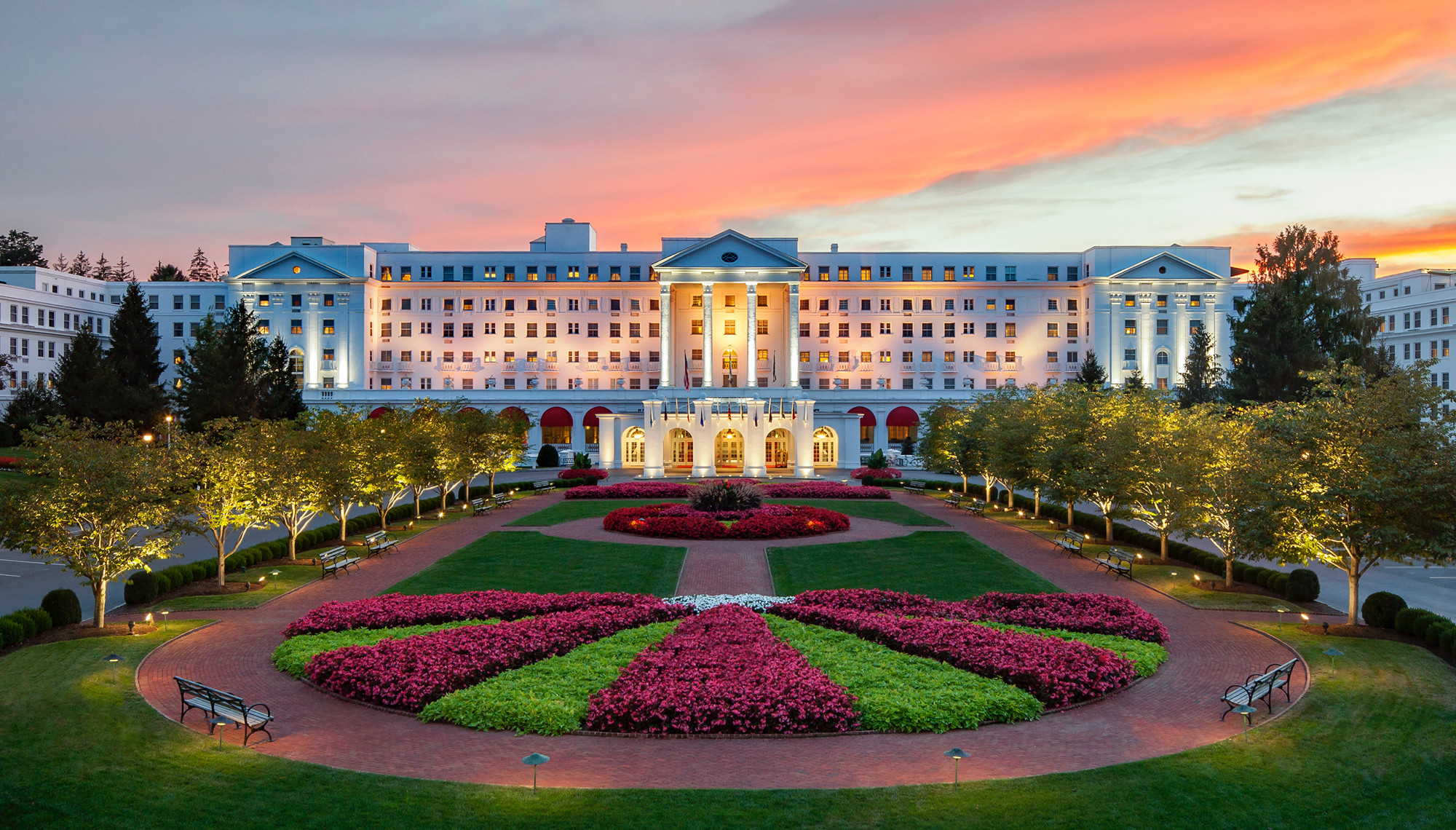 The Greenbrier Resort's grand hotel illuminated by a stunning sunset, casting warm hues across the sky and building