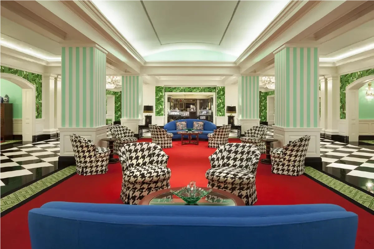 The interior of The Greenbrier resort. Candy apple carpets, houndstooth print chairs and blue couches. The colums have mint striped wallpaper.